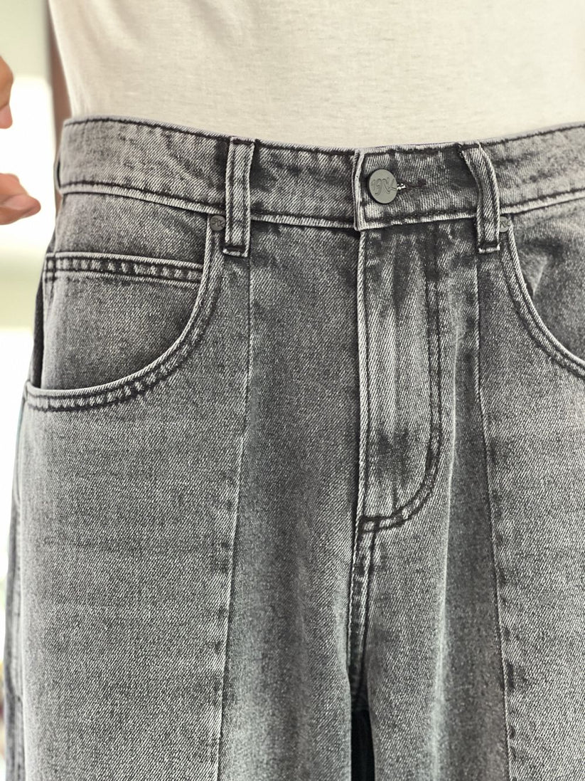Person wearing gray baggy jeans indoors with a blurred background by 1947 clothing