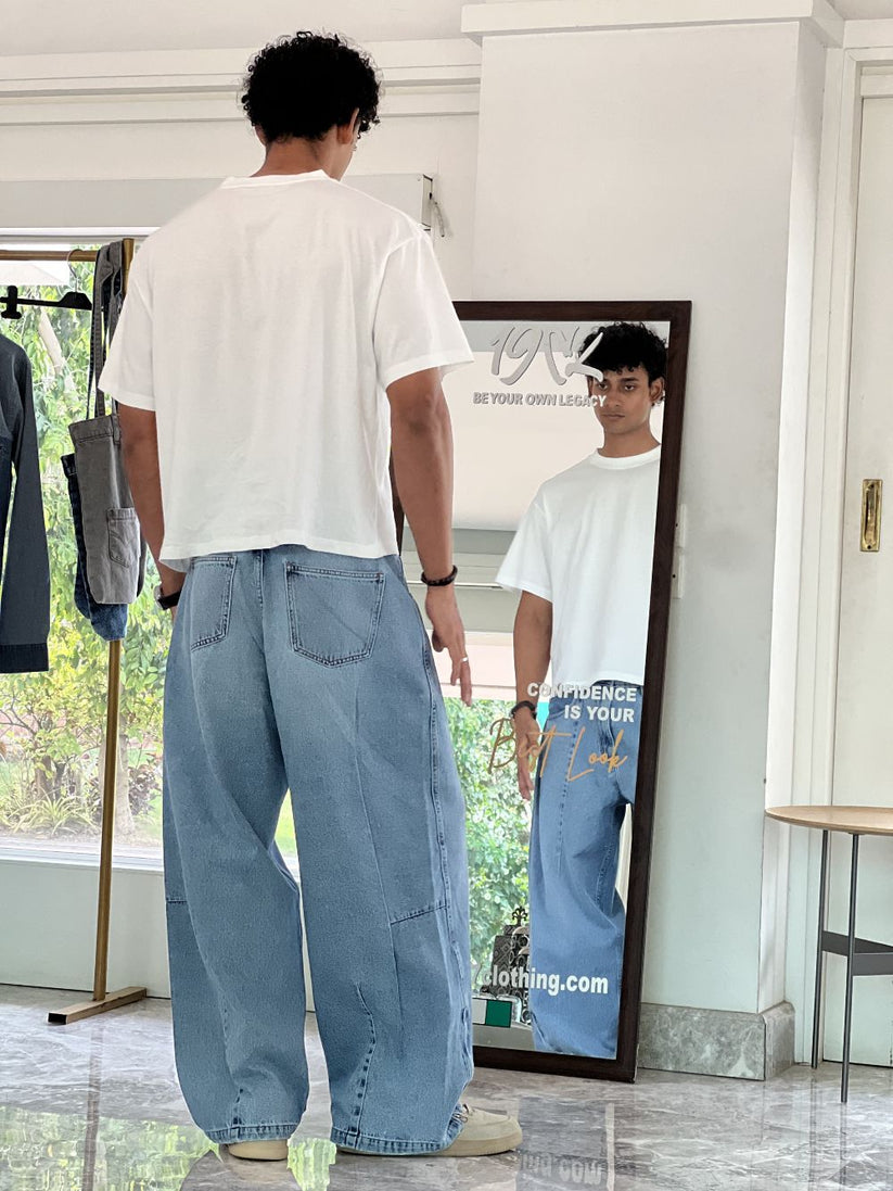 Person wearing light blue baggy jeans with White Boxy Tshirt by 1947 clothing.