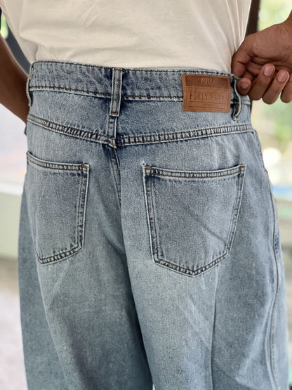 Person wearing light blue baggy jeans with White Boxy Tshirt by 1947 clothing.