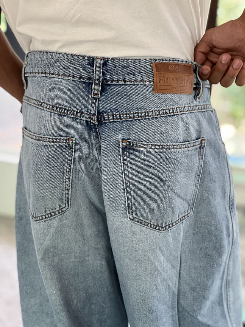 Person wearing light blue baggy jeans with White Boxy Tshirt by 1947 clothing.