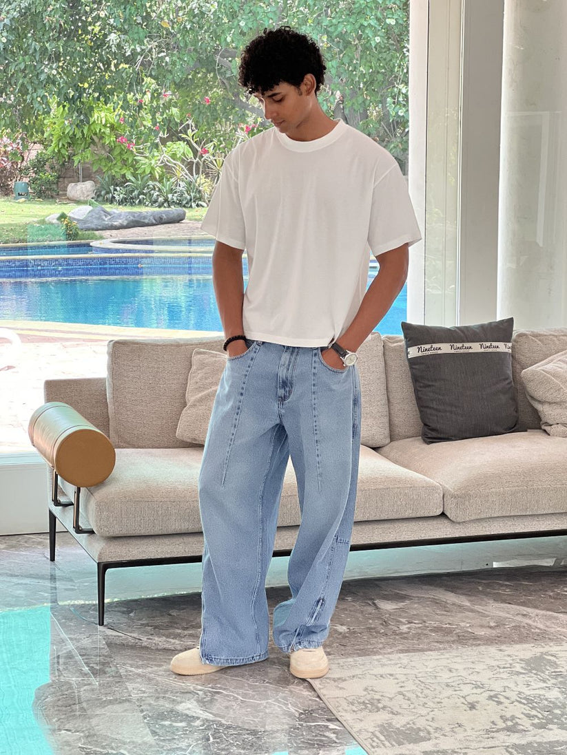 Person wearing light blue baggy jeans with White Boxy Tshirt by 1947 clothing.