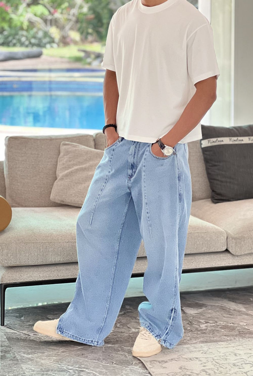 Person wearing light blue wide-leg jeans indoors with a blurred background by 1947 clothing