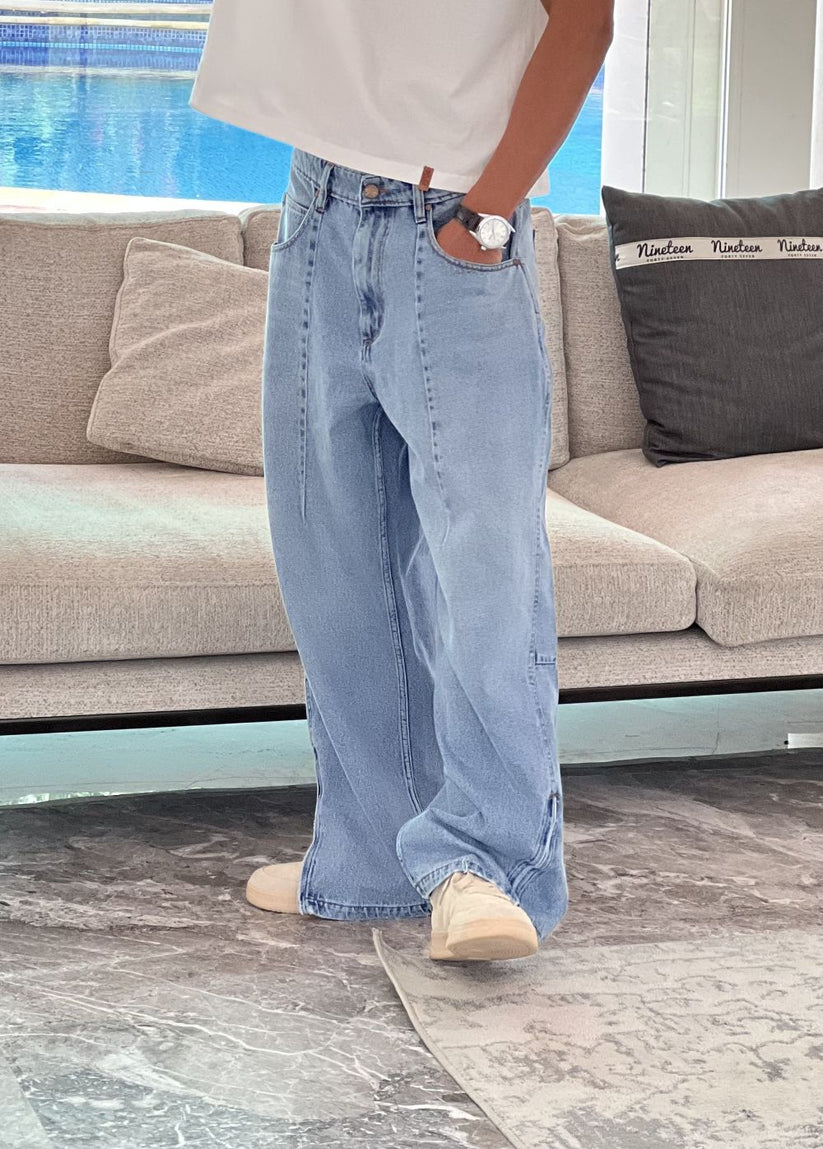 Person wearing light blue baggy jeans with White Boxy Tshirt by 1947 clothing.