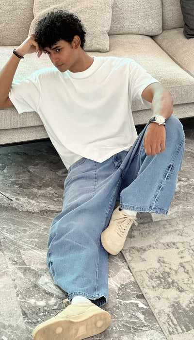 Person wearing light blue baggy jeans with White Boxy Tshirt by 1947 clothing.