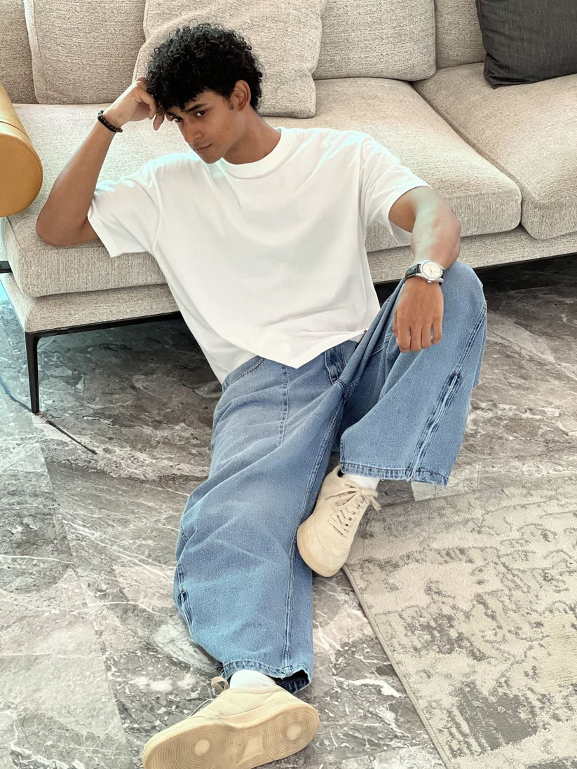 Person wearing light blue baggy jeans with White Boxy Tshirt by 1947 clothing.