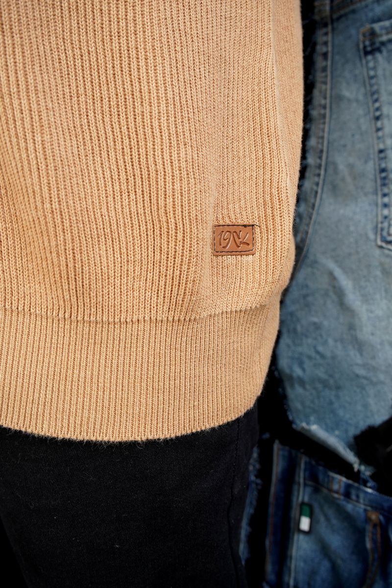 Close-up of Men's Knitted Polo Shirt in a Warm Caramel Tan Color, featuring a Small Brown Leather Logo Patch on the Lower Front by 1947 Clothing
